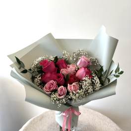 Bouquet of pink roses with baby's breath in pale wrapping