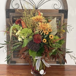 Autumn bouquet of mixed flowers in a glass vase with a striped ribbon