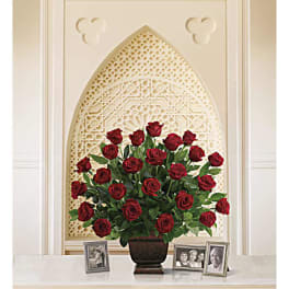 Red roses arranged in a dark vase on a table with framed photos