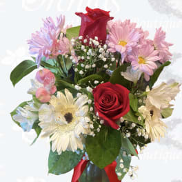 Bouquet of red roses, pink daisies, and white gerbera daisies in a vase