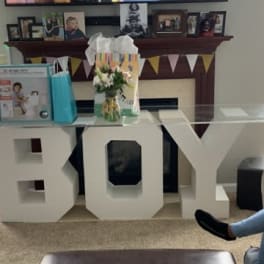 Small flower arrangement beside a large white "BOY" decoration