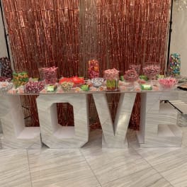 Candy display on a large LOVE sign with a rose-gold backdrop