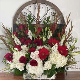 Basket arrangement of red roses, white hydrangeas, and red gerbera daisies