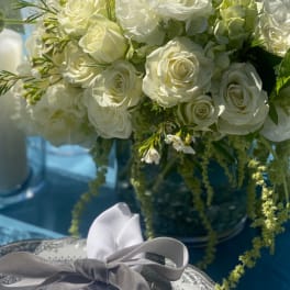 White rose and ranunculus bouquet with green accents and a gray ribbon