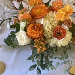 Orange and white floral centerpiece on a dining table