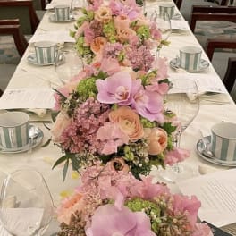 Pink and peach floral centerpieces line a long wedding table