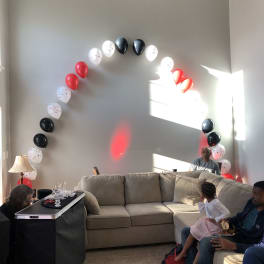 Balloon arch in red, white, and black over a living room sofa