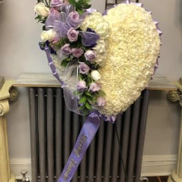 Heart-shaped floral spray with lavender roses and cream blooms on a stand