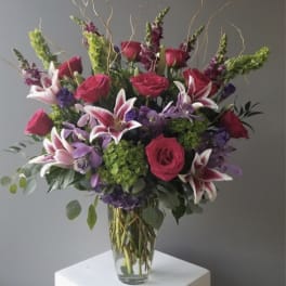 Bouquet of pink roses and purple lilies in a clear glass vase