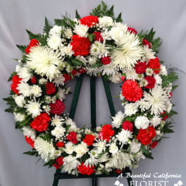 Red and white floral funeral wreath on a stand