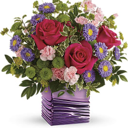 Bouquet of pink roses, purple daisies, and carnations in a purple vase
