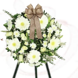 White daisy wreath with a brown bow on a stand