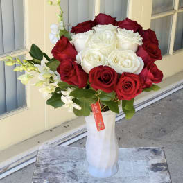 Red and white roses arranged in a white vase