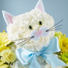 White cat-shaped floral arrangement with a blue bow and yellow flowers