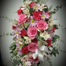 Pink and red mixed flower arrangement with a white ribbon