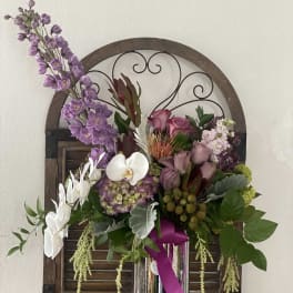 Purple and white floral arrangement in a tall silver vase