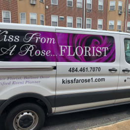 Branded florist van with a purple rose graphic and business text