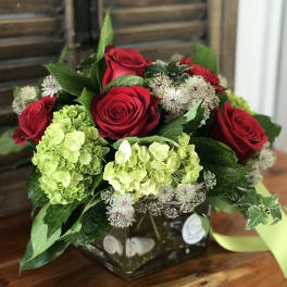Red roses and green hydrangeas in a square glass vase