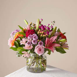 Mixed pink and purple flower bouquet in a clear glass vase