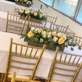 Low floral centerpiece with peach and white roses on a banquet table