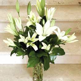 White lilies arranged in a clear glass vase