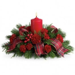 Red candle in a holiday centerpiece with plaid ribbon and greenery