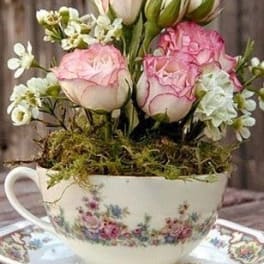 Pink roses arranged in a floral teacup with a matching saucer