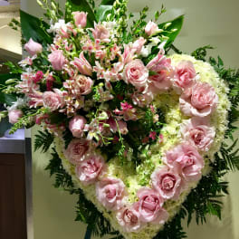Large pink rose and lily funeral spray on an easel