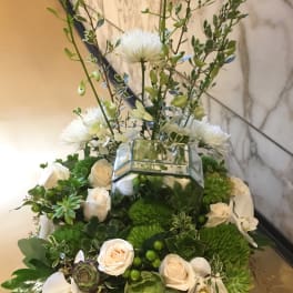 White roses and orchids arranged with succulents in a mirrored box