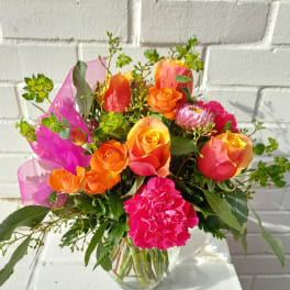 Bouquet of orange and pink roses with carnations in a glass vase