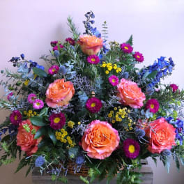 Large mixed bouquet with orange roses and blue flowers in a basket