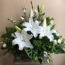 White lilies and small white blooms in a basket arrangement