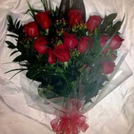 Hand-tied bouquet of red roses wrapped in clear cellophane with a red bow
