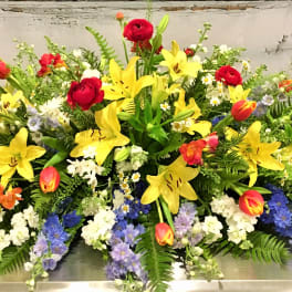 Large mixed floral spray with yellow lilies, red roses, and colorful tulips