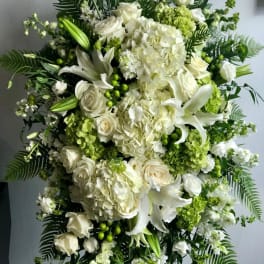 Large white and green floral standing spray with roses, lilies, and hydrangeas