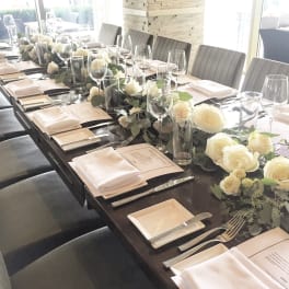 Long dining table set with white rose centerpieces and place settings
