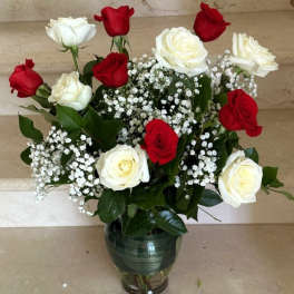 Red and white roses arranged in a glass vase with baby's breath