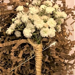 Small bouquet of white flowers wrapped in brown paper