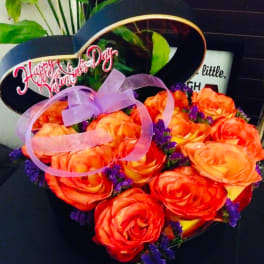 Heart-shaped bouquet of orange roses with a purple ribbon and "Happy Valentine's Day" sign