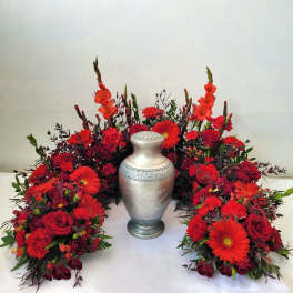 Red floral funeral arrangement surrounding a silver urn