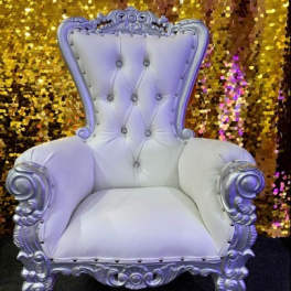 Ornate white tufted throne chair in front of a gold sequin backdrop