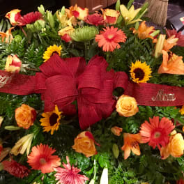 Large floral spray with red ribbon and mixed orange, yellow, and pink flowers