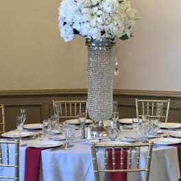 White floral centerpiece on a tall crystal-covered stand
