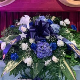Large blue and white funeral spray with ribbons and a bow