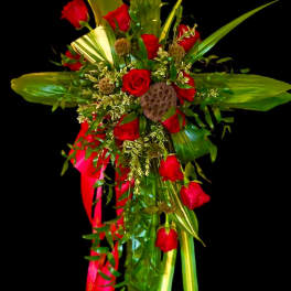 Red roses and tropical greenery arranged with a red ribbon on a black background