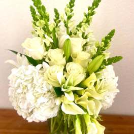 White and pale green floral arrangement in a glass vase