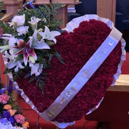 Heart-shaped red floral tribute with white lilies and a ribbon