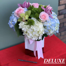 Pink roses and blue hydrangeas in a ribbon-tied box arrangement