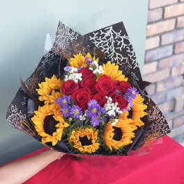 Bouquet of red roses, sunflowers, and purple daisies wrapped in black paper