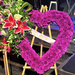 Heart-shaped floral tribute on an easel with pink flowers and lilies